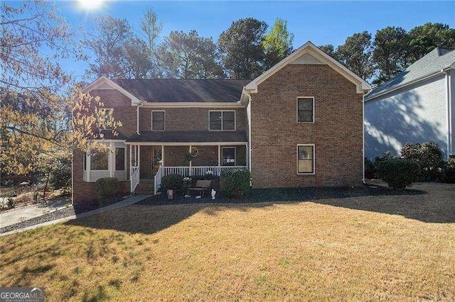 traditional-style home featuring brick siding, covered porch, and a front yard