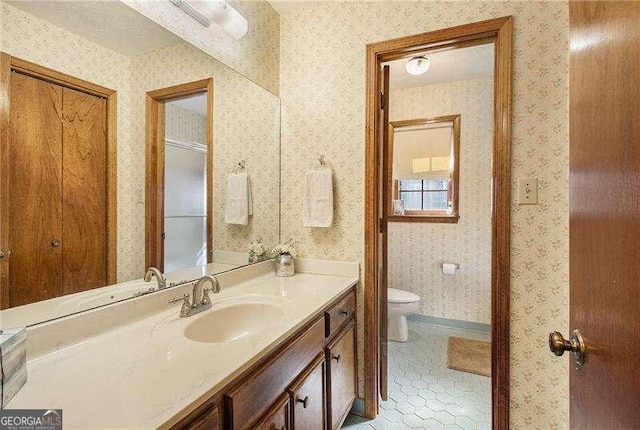 bathroom featuring walk in shower, tile patterned flooring, vanity, toilet, and wallpapered walls
