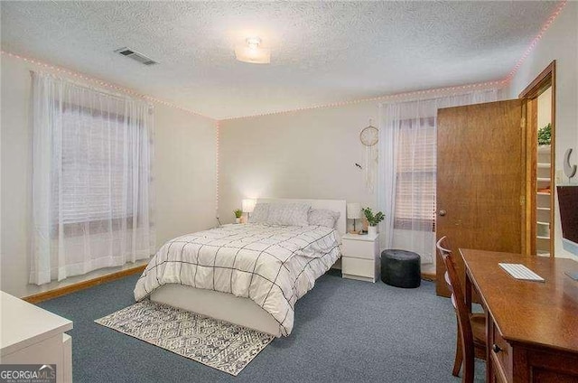 carpeted bedroom featuring a textured ceiling and visible vents