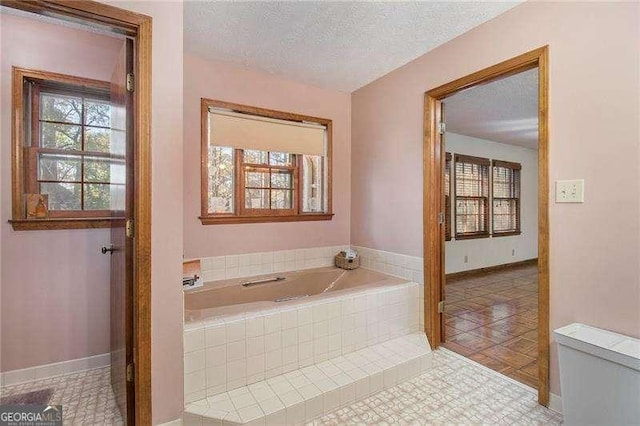 full bathroom featuring a textured ceiling, tile patterned flooring, baseboards, and a bath