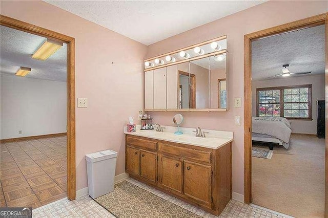 ensuite bathroom featuring baseboards, a sink, a textured ceiling, and ensuite bath
