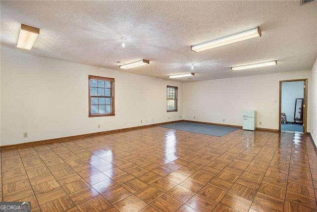 spare room with baseboards and a textured ceiling