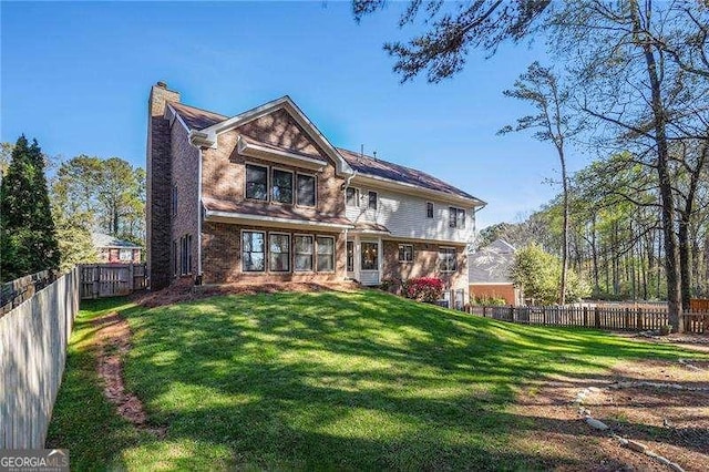 back of house with a lawn, a fenced backyard, and a chimney