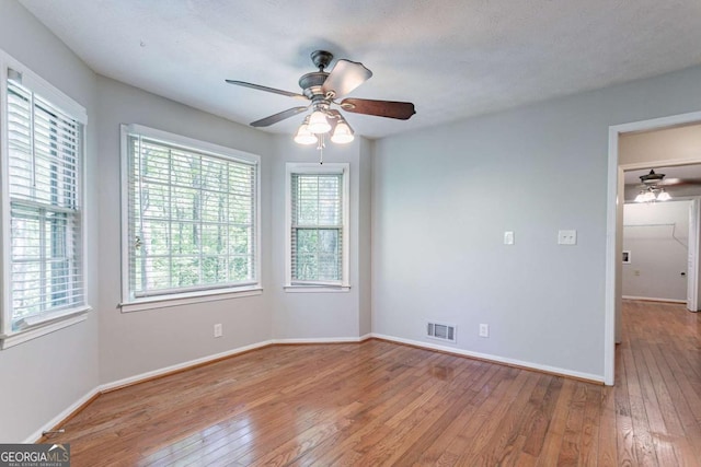 unfurnished room with baseboards, hardwood / wood-style flooring, visible vents, and ceiling fan