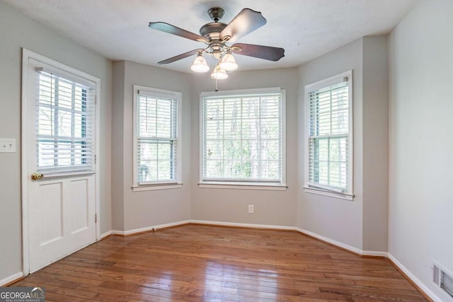 empty room with hardwood / wood-style flooring, baseboards, and a healthy amount of sunlight