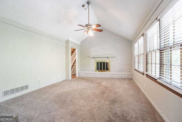 unfurnished living room with vaulted ceiling, visible vents, a ceiling fan, a brick fireplace, and brick wall