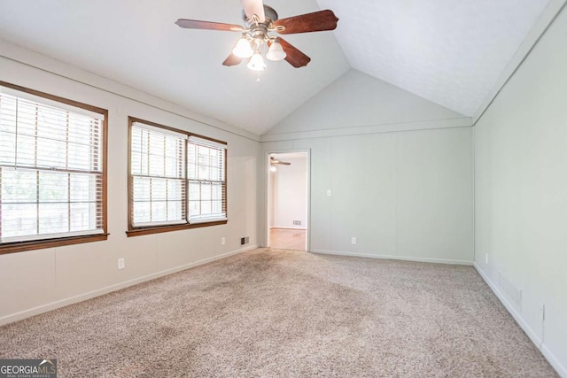 carpeted empty room with vaulted ceiling, a ceiling fan, visible vents, and baseboards