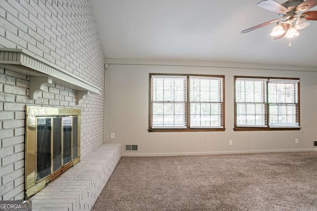unfurnished living room featuring carpet flooring, visible vents, lofted ceiling, ceiling fan, and a fireplace