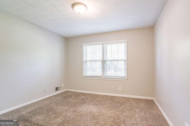 carpeted spare room with baseboards, visible vents, and a textured ceiling