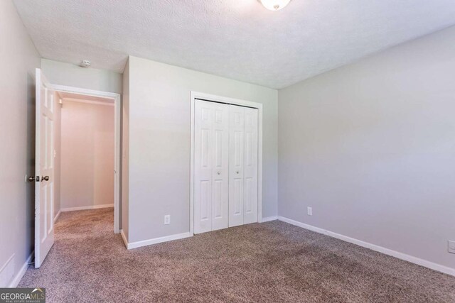 unfurnished bedroom featuring baseboards, carpet, and a closet