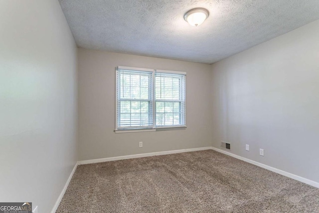 carpeted spare room with baseboards, a textured ceiling, and visible vents