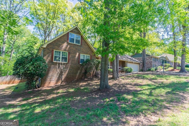 view of front of home featuring fence, brick siding, and a garage