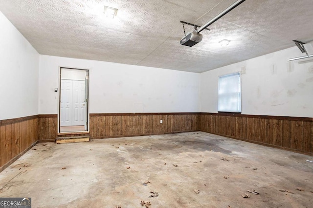 garage with wainscoting, wood walls, and a garage door opener