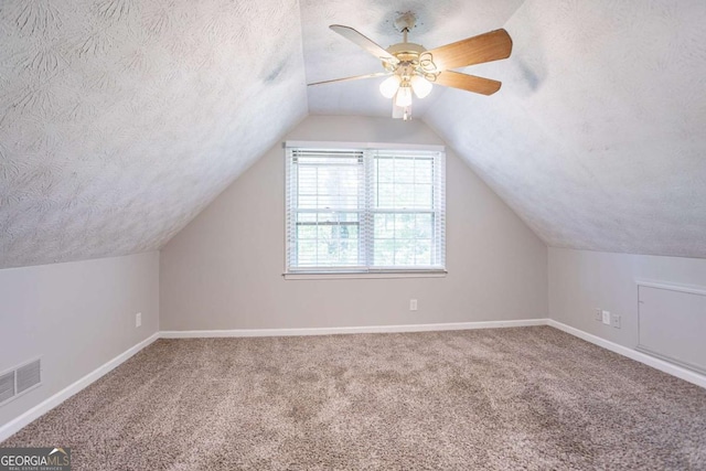 bonus room with carpet floors, a textured ceiling, a ceiling fan, and visible vents