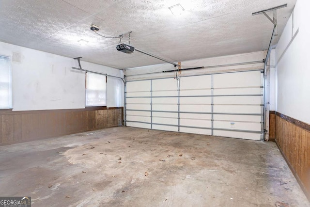 garage with wainscoting, wooden walls, and a garage door opener