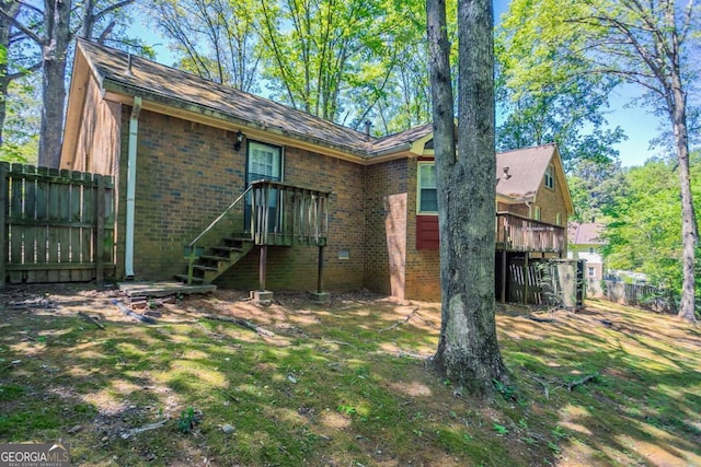 rear view of property featuring fence, a wooden deck, brick siding, and stairway