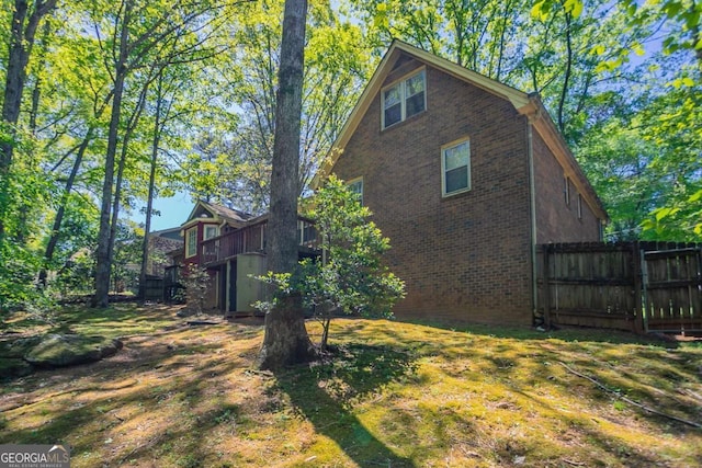 view of property exterior with fence and brick siding