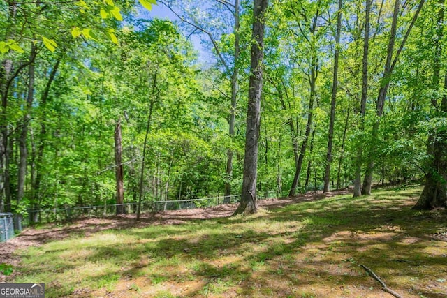 view of yard with a forest view and fence