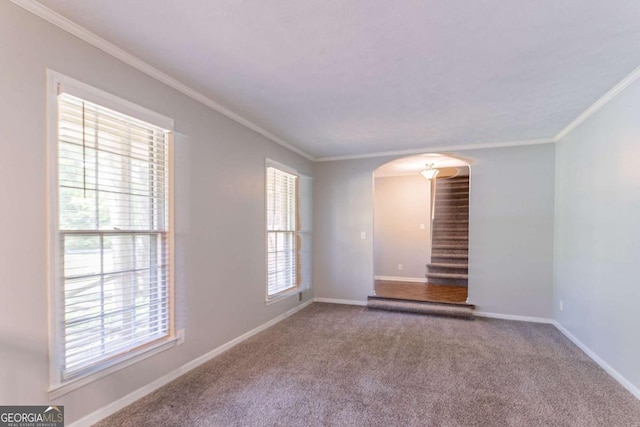 carpeted empty room with stairway, baseboards, arched walkways, and ornamental molding