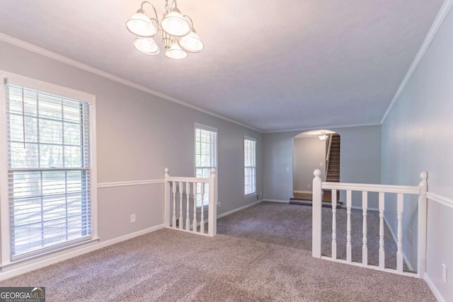 spare room featuring a wealth of natural light, arched walkways, an inviting chandelier, and carpet