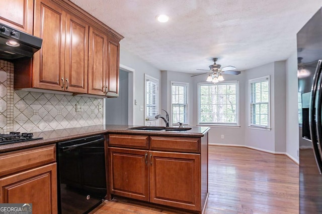 kitchen featuring a sink, black appliances, light wood-style flooring, a peninsula, and ventilation hood