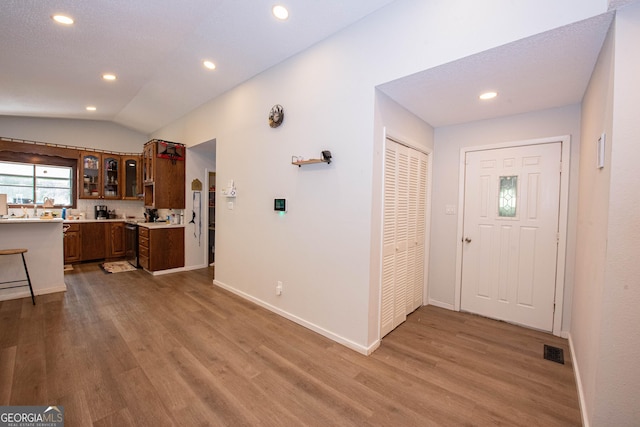 foyer with lofted ceiling, wood finished floors, visible vents, and recessed lighting