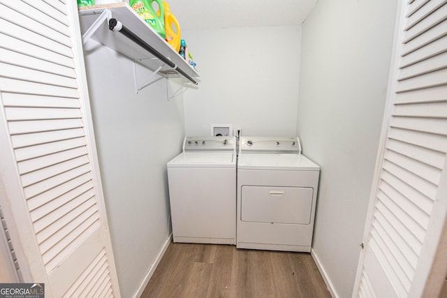 washroom with washing machine and dryer, baseboards, wood finished floors, and laundry area