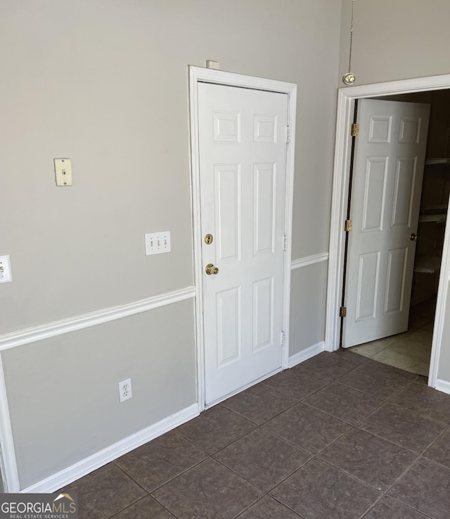 interior space with baseboards and dark tile patterned flooring