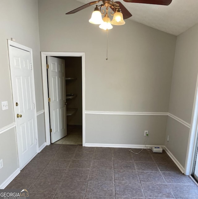 unfurnished room featuring a ceiling fan, baseboards, and dark tile patterned flooring