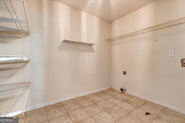 laundry area featuring baseboards, hookup for an electric dryer, laundry area, and light tile patterned floors