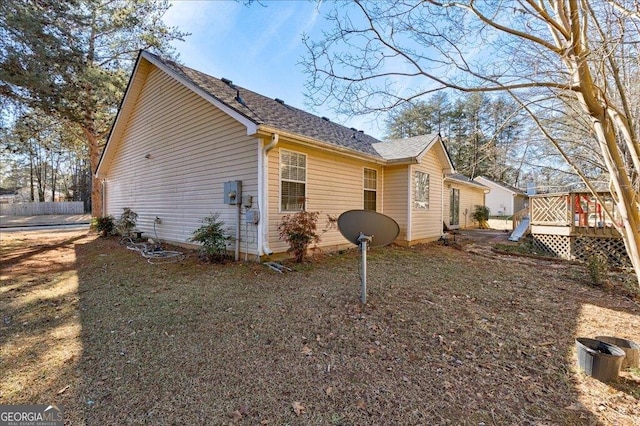 view of side of home featuring fence and a deck