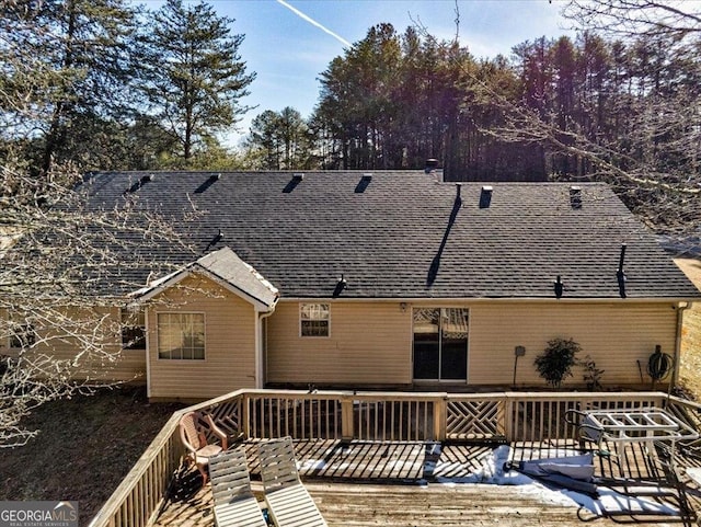 back of property with a wooden deck and roof with shingles
