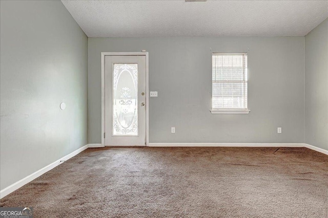 entrance foyer featuring a healthy amount of sunlight, a textured ceiling, and carpet