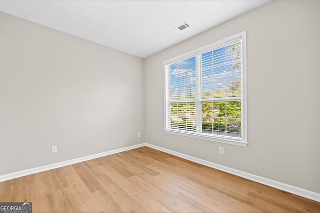 empty room with baseboards, visible vents, and light wood-style floors