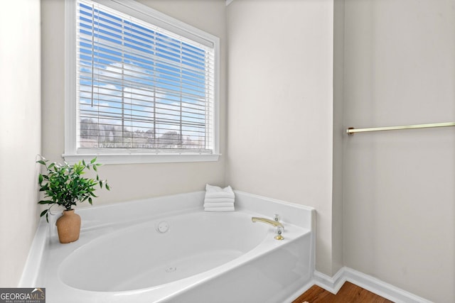 bathroom featuring baseboards, a garden tub, and wood finished floors