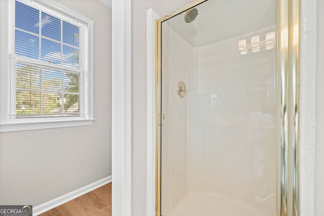 bathroom with wood finished floors, baseboards, and a stall shower
