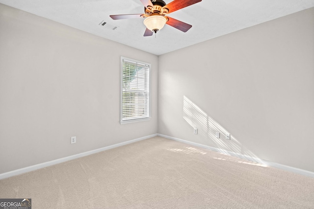 empty room with baseboards, ceiling fan, carpet flooring, and visible vents