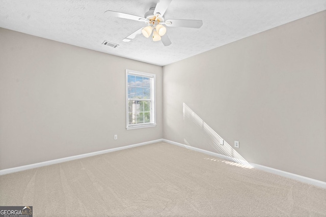 carpeted empty room featuring visible vents, a ceiling fan, baseboards, and a textured ceiling