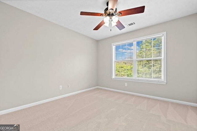 empty room with baseboards, a ceiling fan, visible vents, and light colored carpet