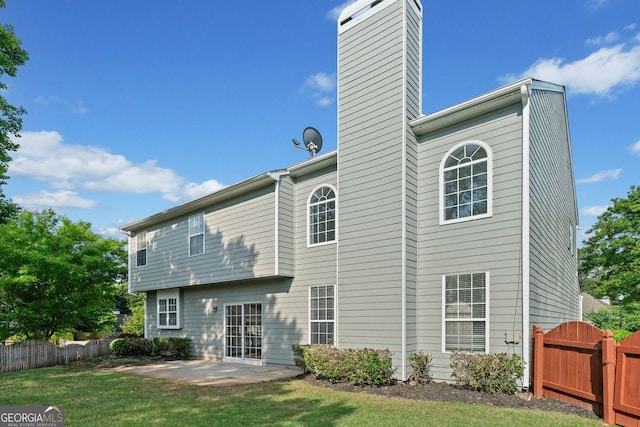 rear view of house featuring fence, a patio, a chimney, and a yard
