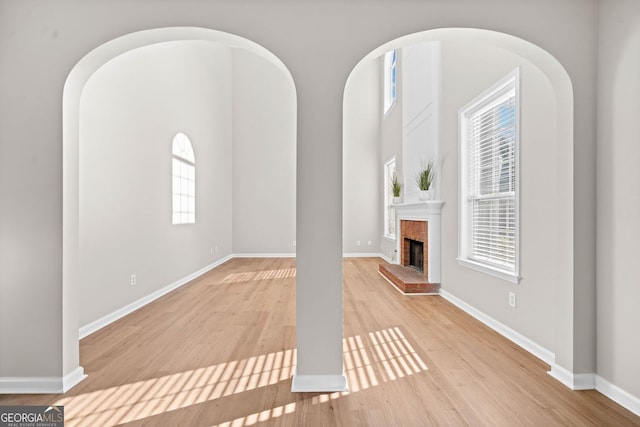 unfurnished living room with baseboards, light wood finished floors, and a fireplace