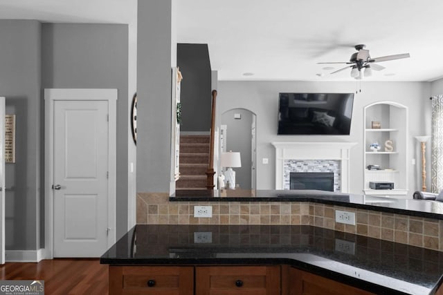 9988 Devonshire St, Douglasville, GA 30135 - kitchen featuring decorative backsplash, ceiling fan, a tile fireplace, open floor plan, and dark wood-type flooring