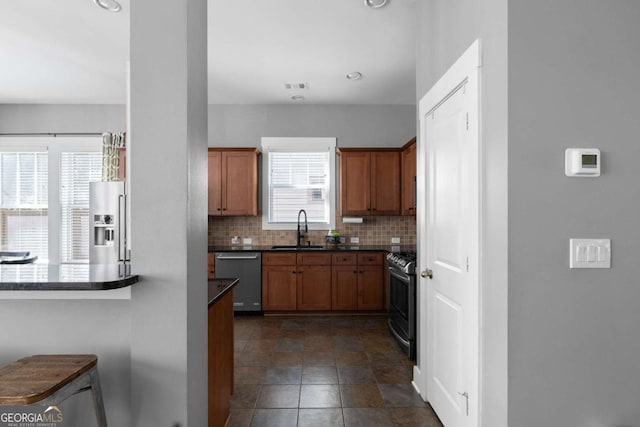 9988 Devonshire St, Douglasville, GA 30135 - kitchen featuring decorative backsplash, dark countertops, brown cabinets, a sink, and appliances with stainless steel finishes