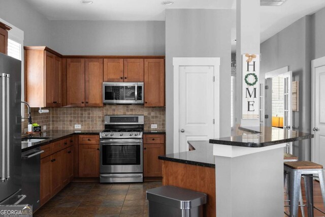 9988 Devonshire St, Douglasville, GA 30135 - kitchen with appliances with stainless steel finishes, a breakfast bar, a sink, brown cabinetry, and tasteful backsplash
