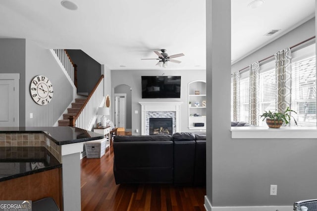 9988 Devonshire St, Douglasville, GA 30135 - living room featuring a ceiling fan, visible vents, a fireplace, stairs, and dark wood-type flooring
