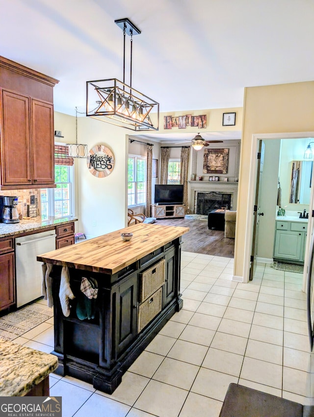 1581 Shetland Pony Ct NW, Suwanee, GA 30024 - kitchen with stainless steel dishwasher, wood counters, light tile patterned floors, and a fireplace