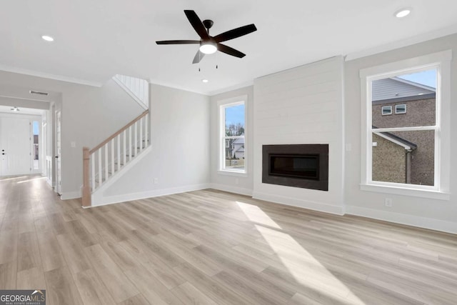 unfurnished living room featuring baseboards, crown molding, stairs, and light wood-style floors