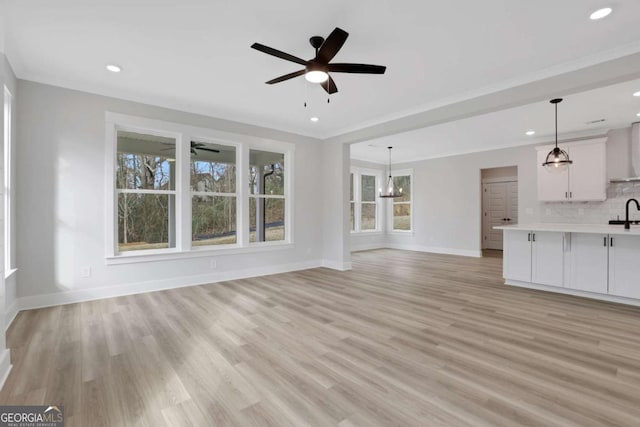 unfurnished living room with baseboards, light wood-style floors, and a healthy amount of sunlight