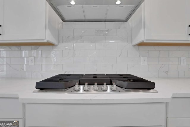 interior details with white cabinets, decorative backsplash, and ventilation hood