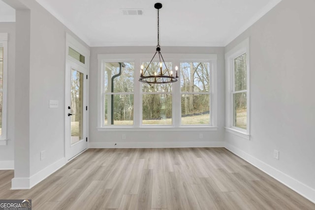 unfurnished dining area with light wood-style flooring, baseboards, visible vents, a chandelier, and crown molding